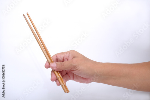 Hand holding bamboo chopsticks over white background