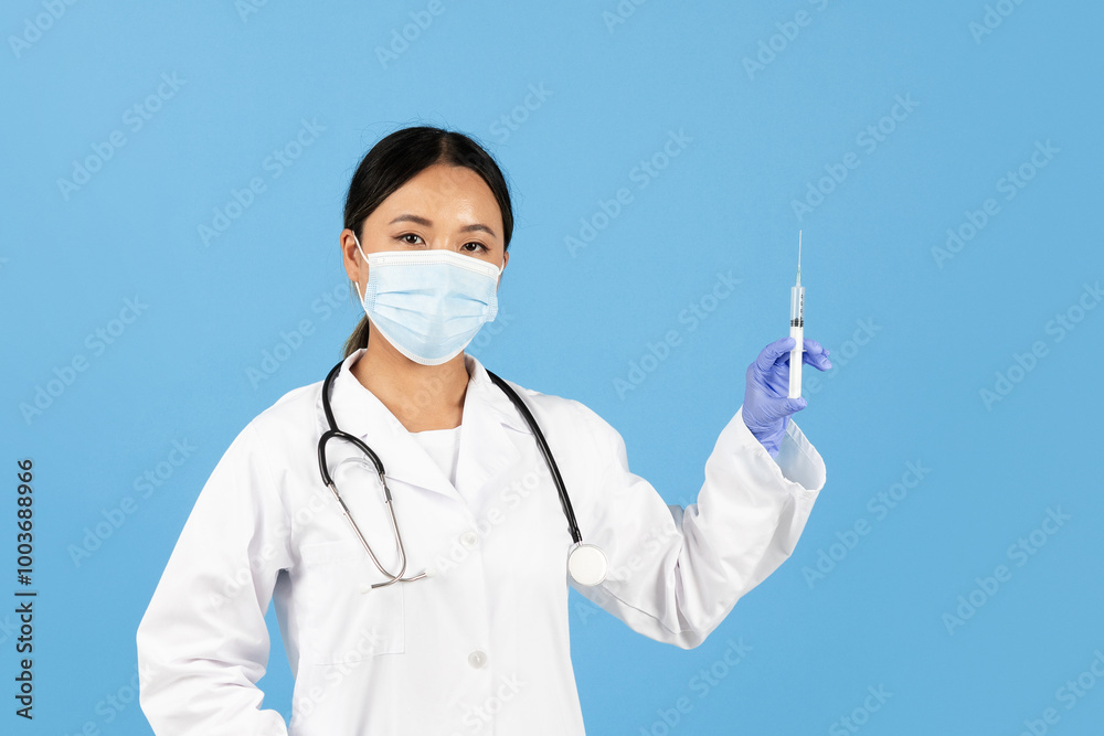 A health professional in a white coat and mask displays a syringe with a gloved hand, preparing for an important medical procedure. The background is a calming blue.