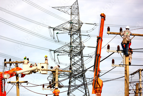group of electrician workers working on crane and lamp post near  high voltage power lines network