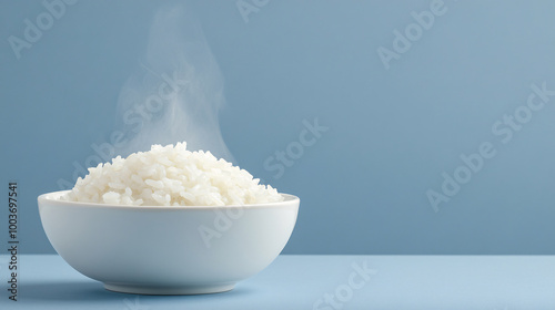 A bowl of freshly cooked white rice steaming against a blue background. photo