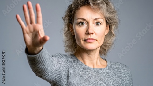 middle aged white woman standing with one hand extended to camera with palm raised in 