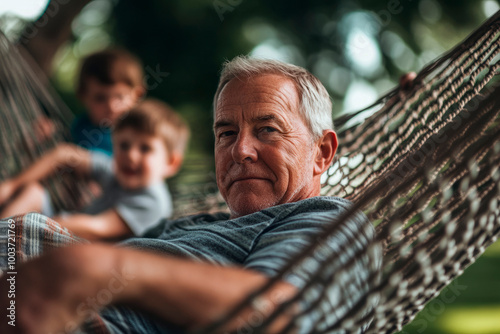 Older man relaxing on a hammock with grandchildren