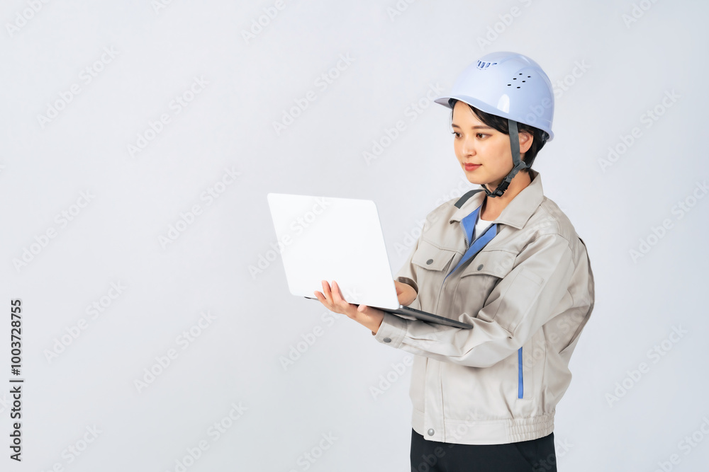 パソコンを持つヘルメットと作業服を着た女性　作業員　エンジニア