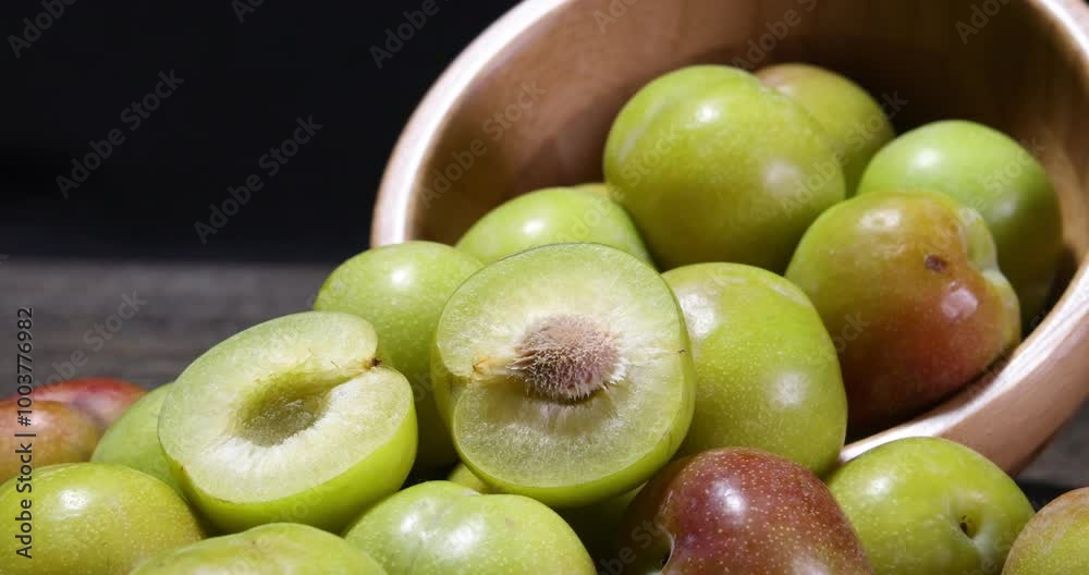 Ripe sweet small mini plum green maroon on rustic wooden table bowl black background Ripe sweet small mini plum green maroon on rustic wooden table bowl black background