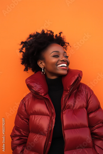 Beautiful Black woman laughing and wearing an oversized burgundy puffer The vibrant and bright solid orange background, street style , life style aesthetic