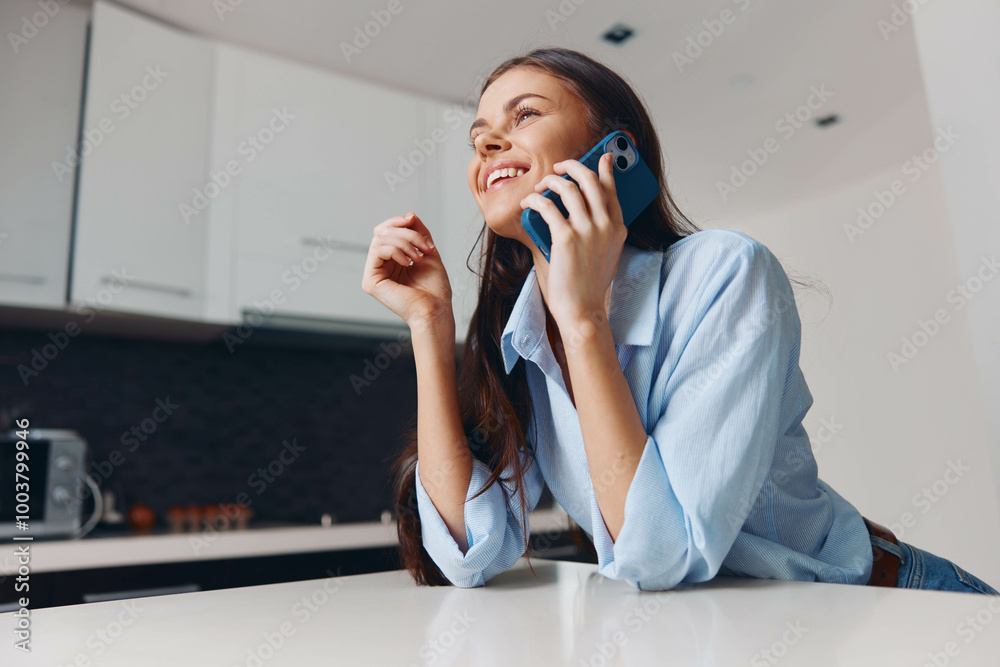 Busy woman talking on phone at table in contemporary kitchen interior Busy woman talking on phone at table in contemporary kitchen interior