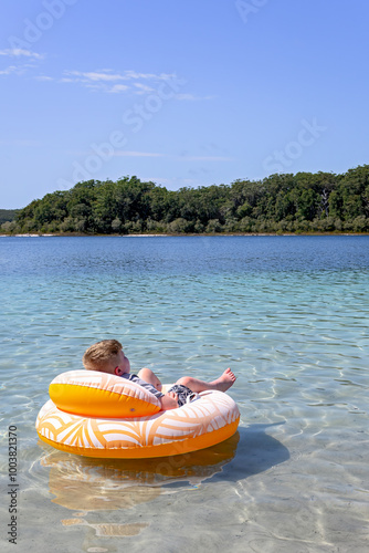 Boy relaxing floating on Lake McKenzie, Boorangoora, K'gari Fraser Island, holiday vacation travel destination, Queensland Australia photo