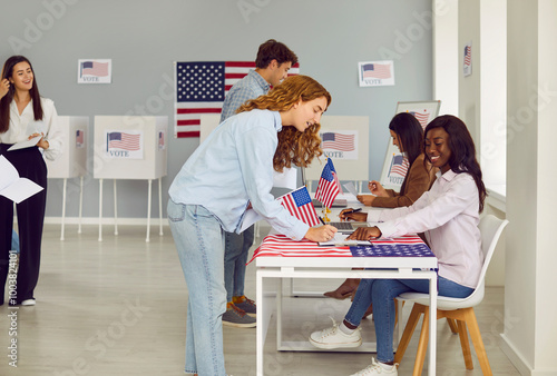 Fotografi Side view portrait of smiling happy young girl american citizen registering at polling station with American flags on election day