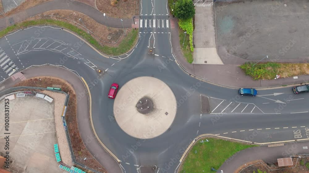An aerial view of a roundabout with cars navigating the lanes. The ...