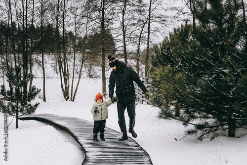 father and daughters are playing in the backyard of the house in the winter snowy season