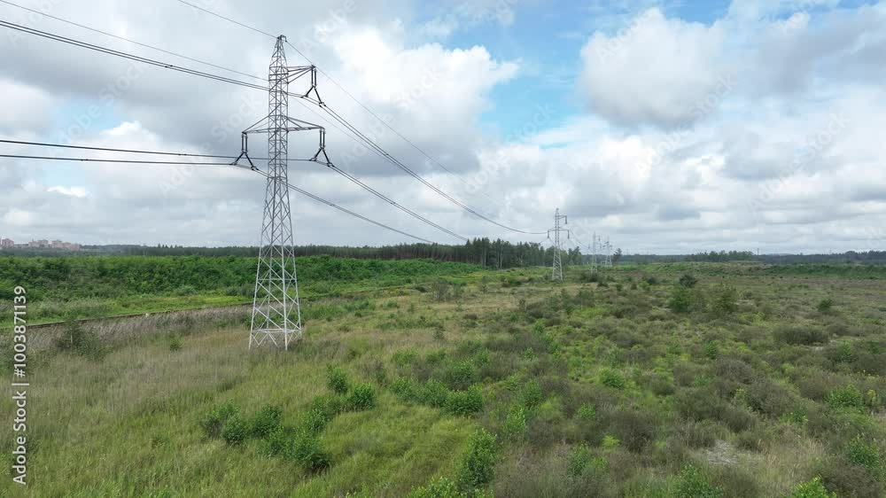 The drone shot shows a high-voltage power line stretching across an open meadow.