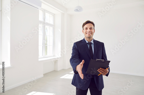 Bild auf Leinwand Portrait of a happy real estate agent extends hand for a handshake in an empty home or office