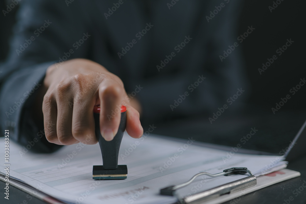Close-up Of A Person's Hand Stamping With Approved Stamp On Text Approved Document At Desk, Contract Form Paper Close-up Of A Person's Hand Stamping With Approved Stamp On Text Approved Document At Desk, Contract Form Paper