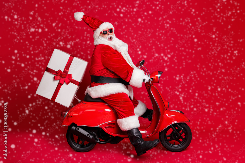 Full length profile photo of retired grandpa white beard ride vintage motorbike high speed late deliver present wear santa x-mas costume coat sunglass cap isolated red color background Full length profile photo of retired grandpa white beard ride vintage motorbike high speed late deliver present wear santa x-mas costume coat sunglass cap isolated red color background