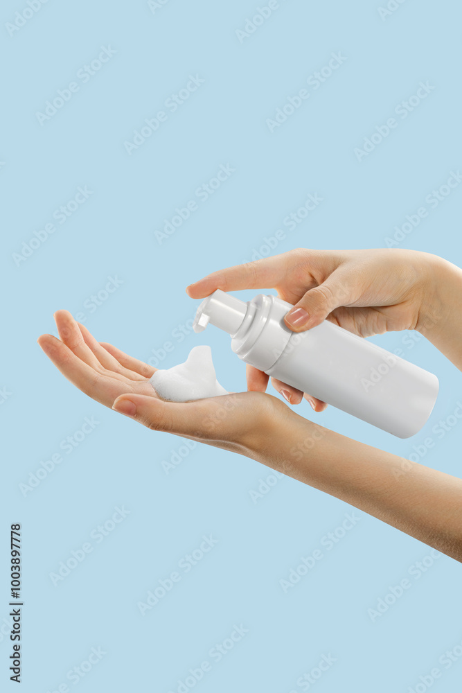 person applying a frothy skincare product from a white pump bottle into their palm against a light blue background, showcasing a skincare routine focusing on self-care and wellness. The activity empha