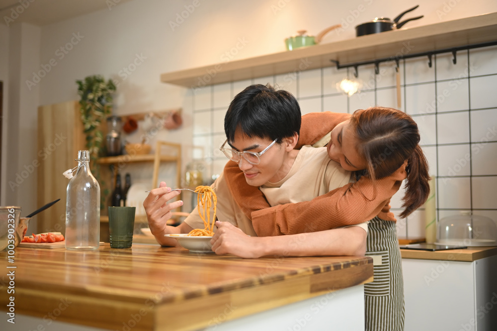 Affectionate young couple chatting and enjoying their lunch in domestic kitchen Affectionate young couple chatting and enjoying their lunch in domestic kitchen