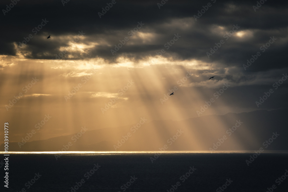 The sun's rays break through the clouds and create a beautiful atmosphere - the island of La Gomera in the background.
