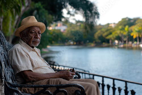 Elderly man sitting peacefully by a lake, holding a bottle of oil photo