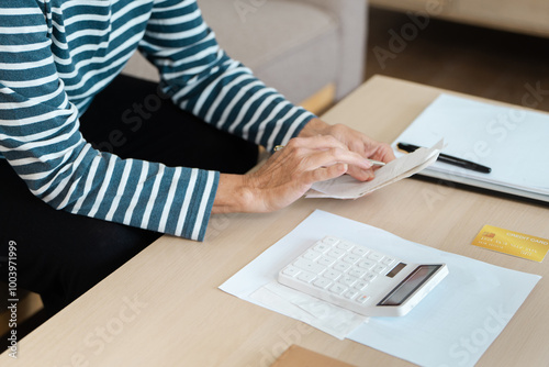 Senior Citizen Managing Finances with Calculator and Credit Card at Home, Concept of Retirement and Banking