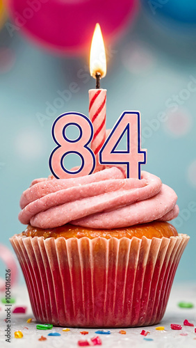 Birthday cupcake with burning lit candle with number 84. Number eighty-four for eighty-four years or eighty-fourth anniversary. photo