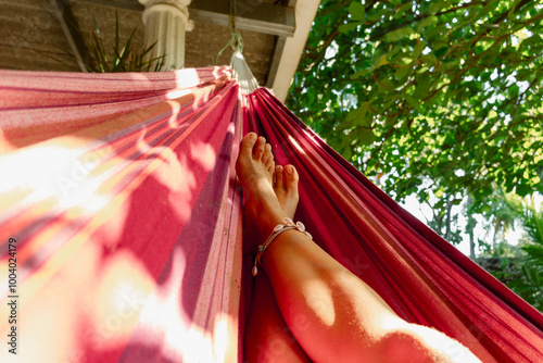 Relaxed barefoot perspective from a hammock under trees