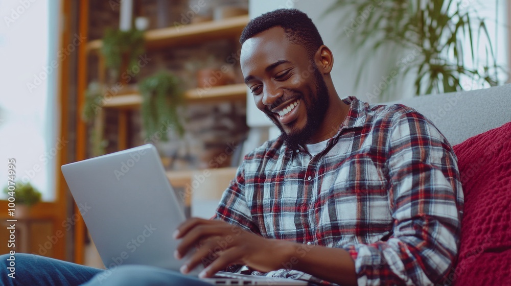 A man is sitting on a couch and smiling while using a laptop A man is sitting on a couch and smiling while using a laptop