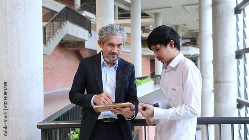 Asian senior professor is giving advice to the college student on the research thesis while sitting in the university faculty for education, academic and business