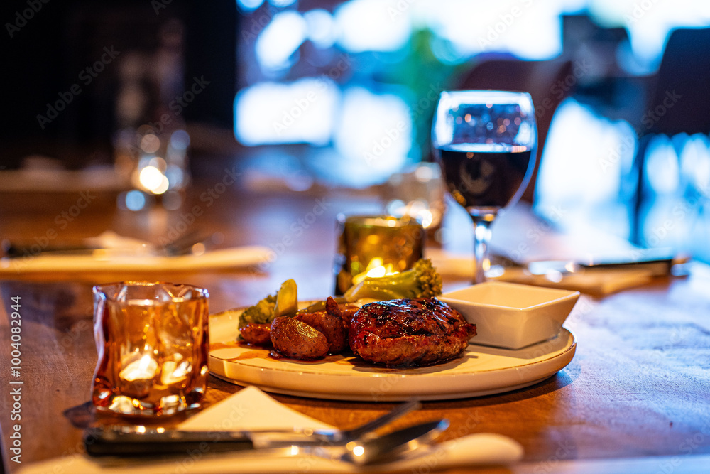 Beef steak meat with vegetables and sauce served with red wine and candles Beef steak meat with vegetables and sauce served with red wine and candles