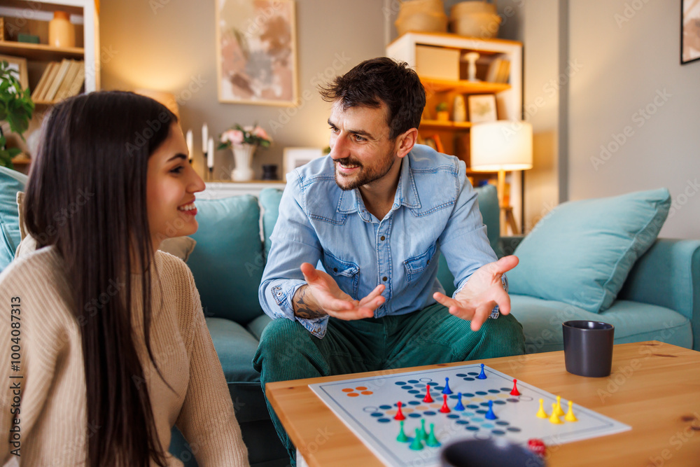 Fototapeta premium Couple playing ludo board game while relaxing at home