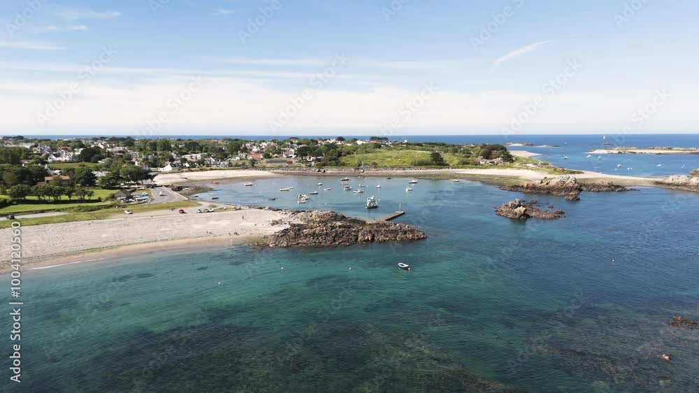 Guernsey Bordeaux Harbour. Drone flight over beaches approaching the harbour entrance with crystal clear water, rocks and boats at anchor on bright sunny day