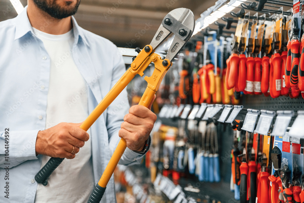 With garden shears. Man is in the hardware shop With garden shears. Man is in the hardware shop