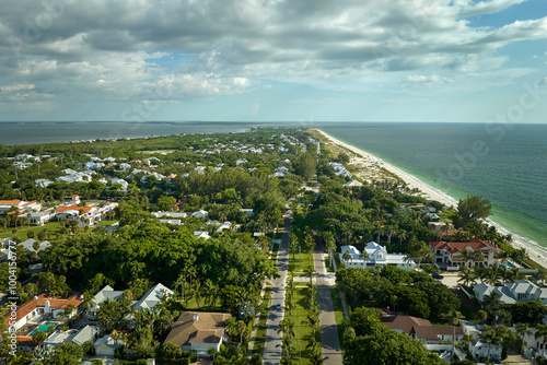 Expensive mansions between green palm trees on Gulf of Mexico shore in island small town Boca Grande on Gasparilla Island in southwest Florida, USA. Aerial view of wealthy waterfront neighborhood photo