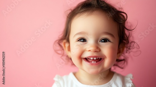 A baby with brown hair and brown eyes smiles broadly at the camera.