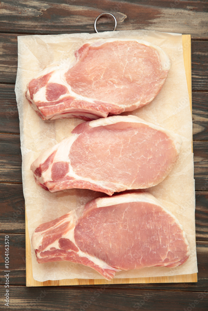 Sliced raw pork meat on cutting board on brown wooden background. Vertical photo Sliced raw pork meat on cutting board on brown wooden background. Vertical photo