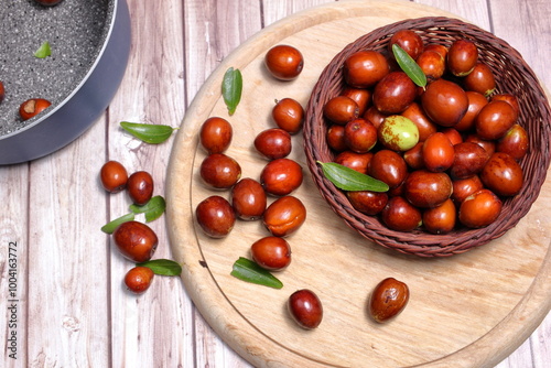 Group of ripe jujubes arranged on wooden cutting board.