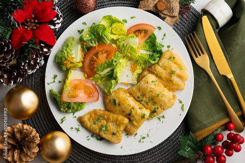 Tempura hake pieces with salad. Top view table with Christmas decoration.