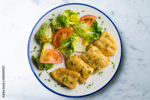 Tempura hake pieces with salad. Top view table with decoration.