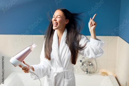 Φωτογραφία Playful European woman singing while drying hair with hairdryer at home in bathr