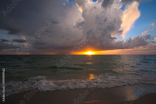 Rainstorm clouds over rough sea waters. Evening ocean waves crushing on sandy beach. Beautiful seascape at sunset