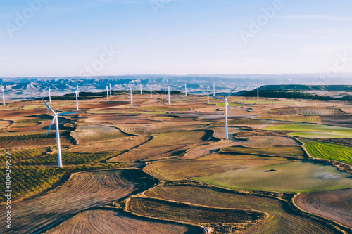 Aerial view of windmills station with rotating propellers generating alternative clean green power from eco resources in rural agri environment.Birds eye view of line of turbines producing electricity photo