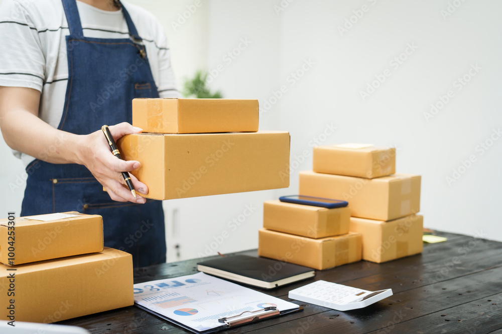 A man is working at his desk, preparing parcel boxes for shipment. He checks and packs items carefully, using shockproof materials, and attaches labels before sending them to customers via EMS. A man is working at his desk, preparing parcel boxes for shipment. He checks and packs items carefully, using shockproof materials, and attaches labels before sending them to customers via EMS.