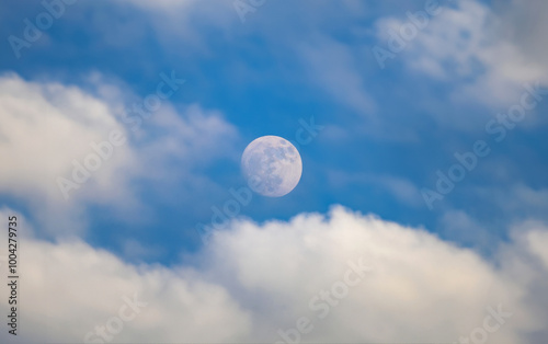 Beautiful cloudscape with bright blue sky and moon in foreground, perfect for serene nature photography.