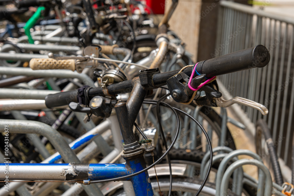 Old bicycle with worn handlebars parked in a row with other bikes Old bicycle with worn handlebars parked in a row with other bikes