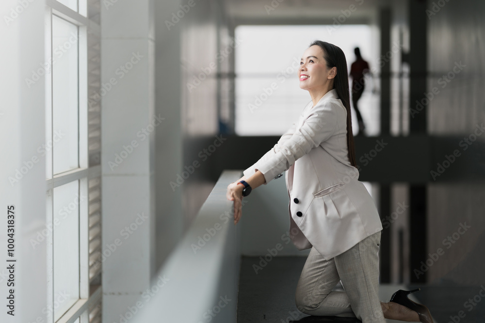 Smiling Businesswoman Leaning by Office Window. A cheerful businesswoman leans against a window in a modern office, exuding confidence and positivity, representing leadership and success. Smiling Businesswoman Leaning by Office Window. A cheerful businesswoman leans against a window in a modern office, exuding confidence and positivity, representing leadership and success.