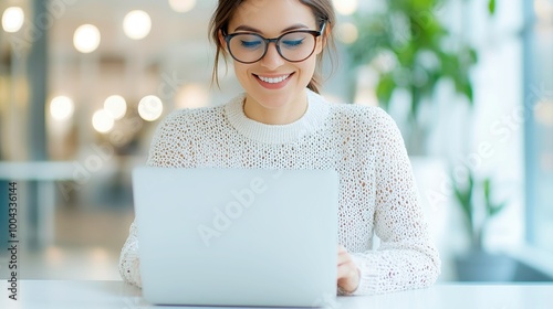 Confident businesswoman engaged in work at modern corporate office, bright smile, focused on laptop, professional attire, contemporary workspace ambiance, fostering productivity and collaboration