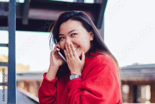 Cheerful female teenager enjoying friendly smartphone conversation for intriguer gossiping and rumors, happy chinese hipster girl making international smartphone conversation connected to roaming