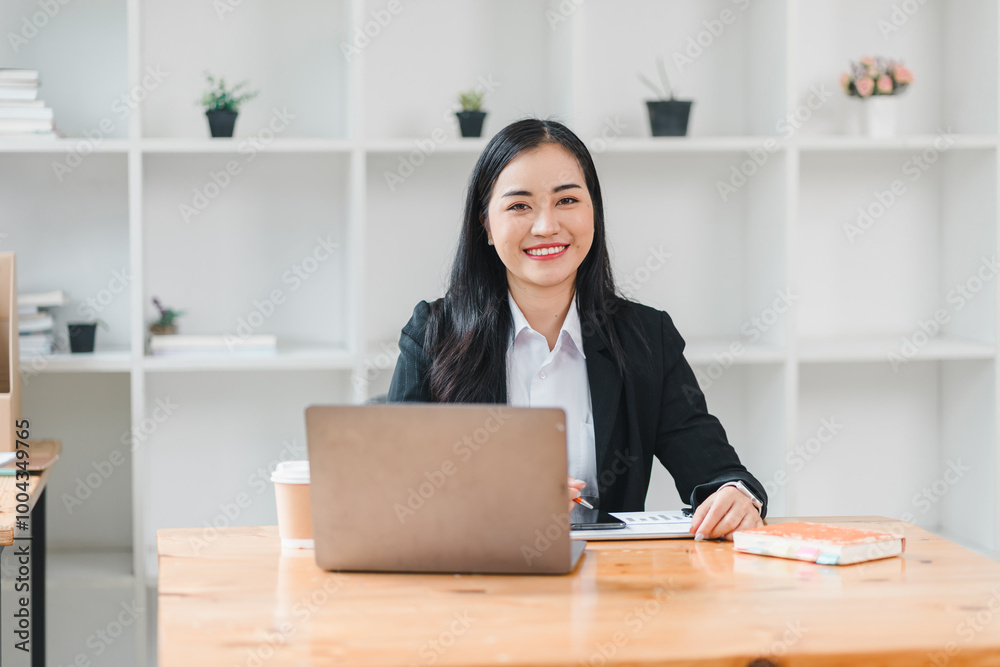 professional woman is smiling confidently while sitting at desk with laptop, notebook, and coffee cup in modern office setting. atmosphere is bright and inviting, perfect for productivity. professional woman is smiling confidently while sitting at desk with laptop, notebook, and coffee cup in modern office setting. atmosphere is bright and inviting, perfect for productivity.