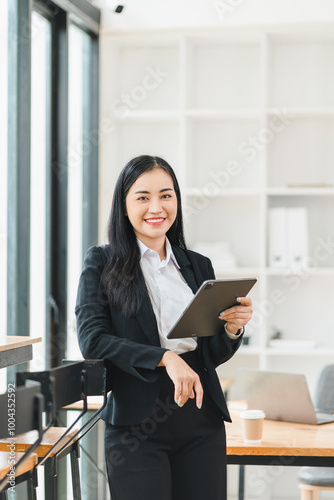 confident businesswoman stands in modern office, holding tablet and smiling. Her professional attire and bright workspace create inspiring atmosphere for productivity. Free Download confident businesswoman stands in modern office, holding tablet and smiling. Her professional attire and bright workspace create inspiring atmosphere for productivity. - GFXLoad
