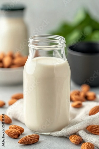 Almond milk in a glass bottle with almonds and a cloth background
