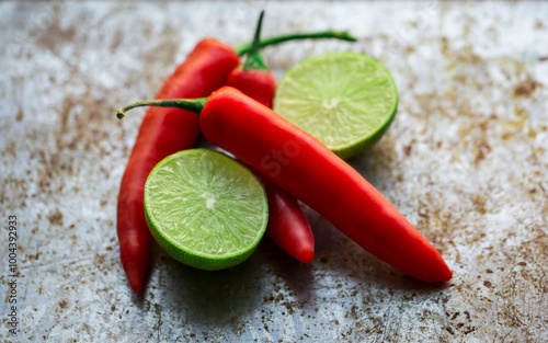 Fresh red chili peppers and halved limes on a rustic wooden surface. photo